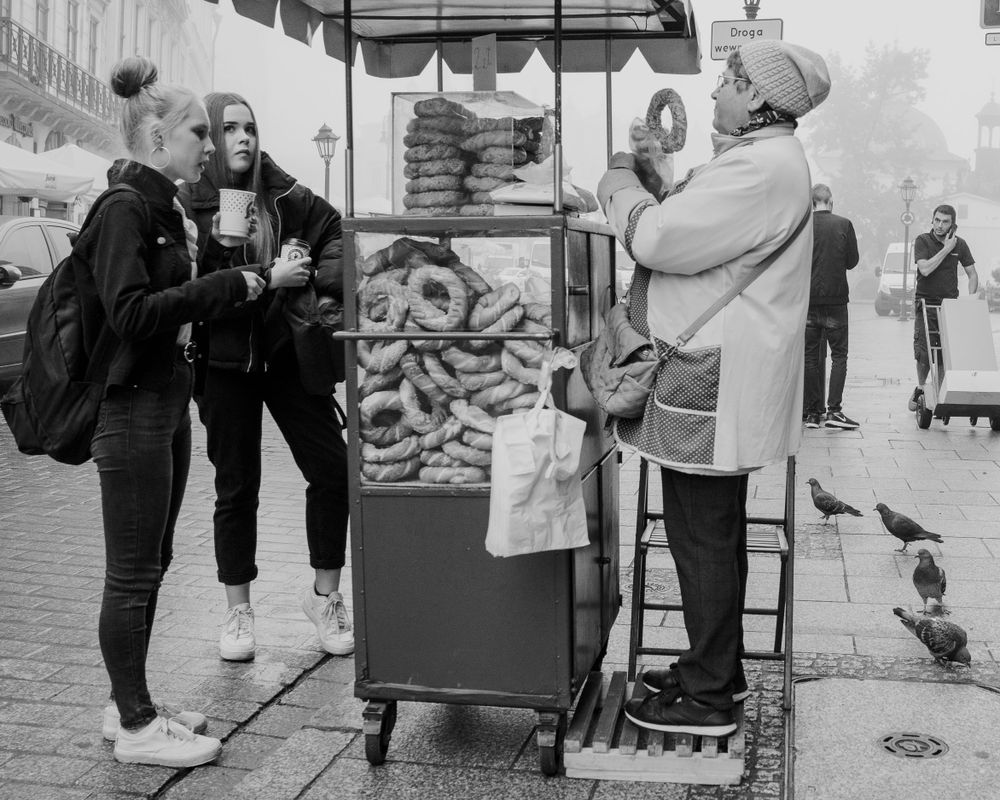Street vendors and pedestrians walking near market stalls in black and white.