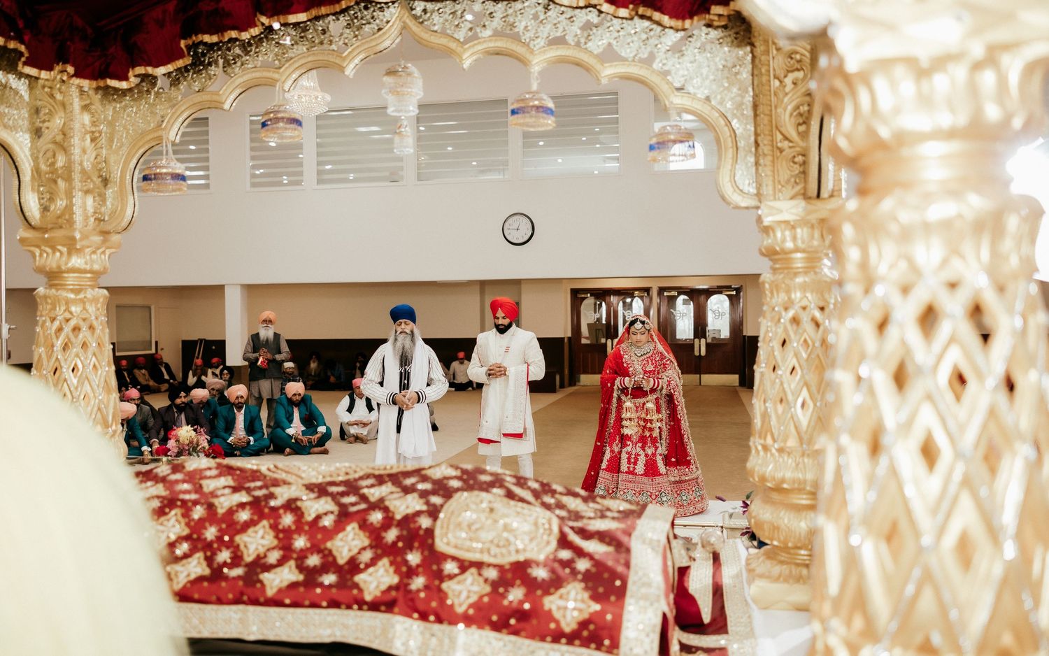 A Sikh wedding ceremony taking place under decorative golden arches.