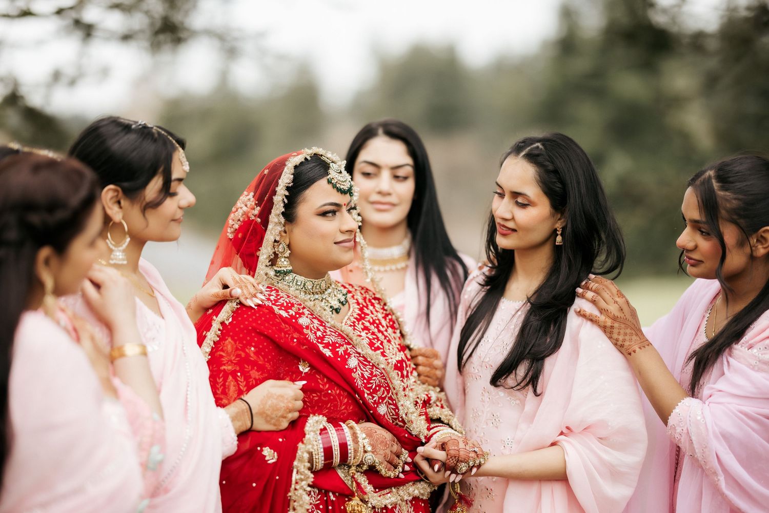 Close-up of bridal party sharing intimate moment with bride in red traditional attire.