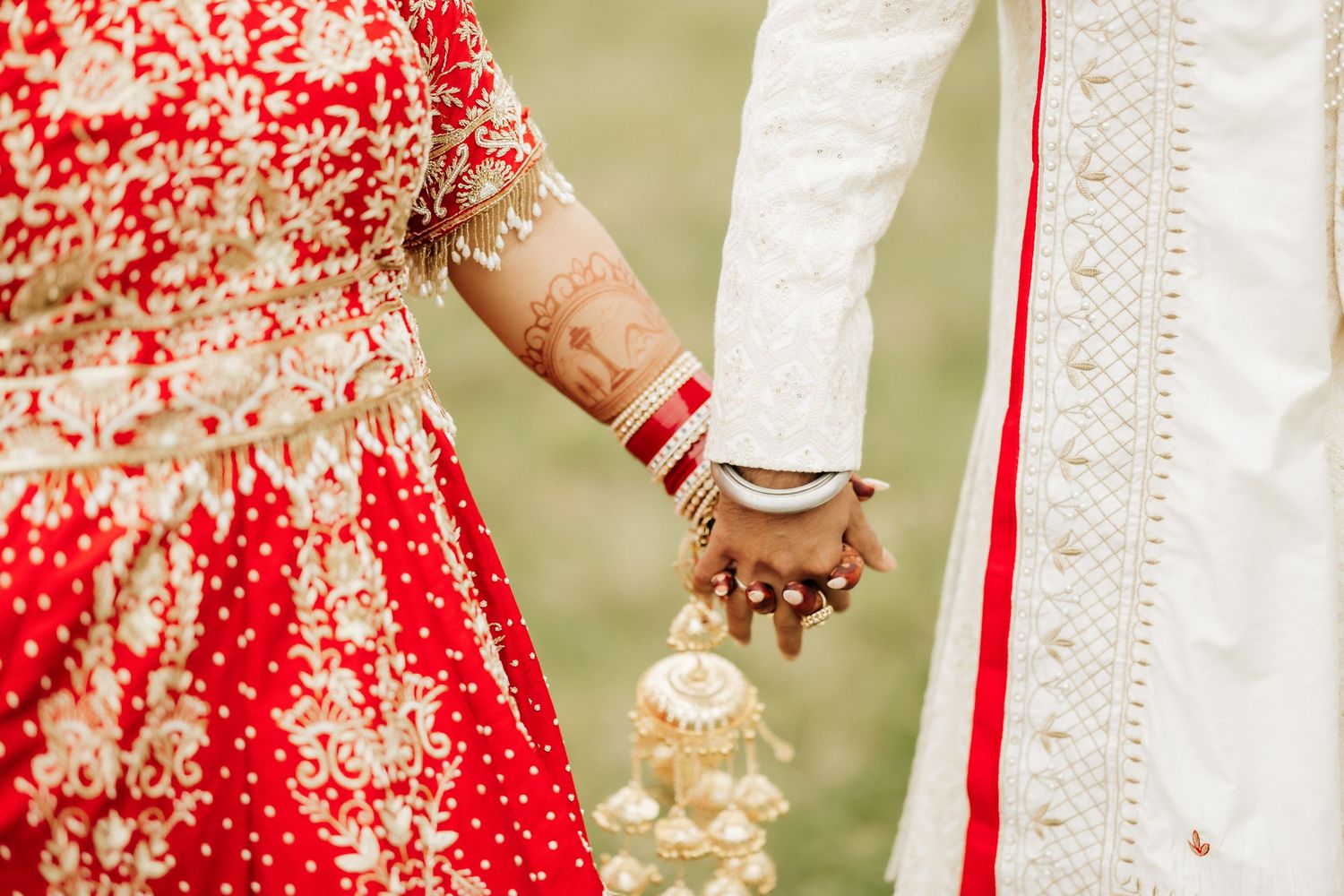 A close-up of decorated hands holding together, showing traditional wedding attire details.