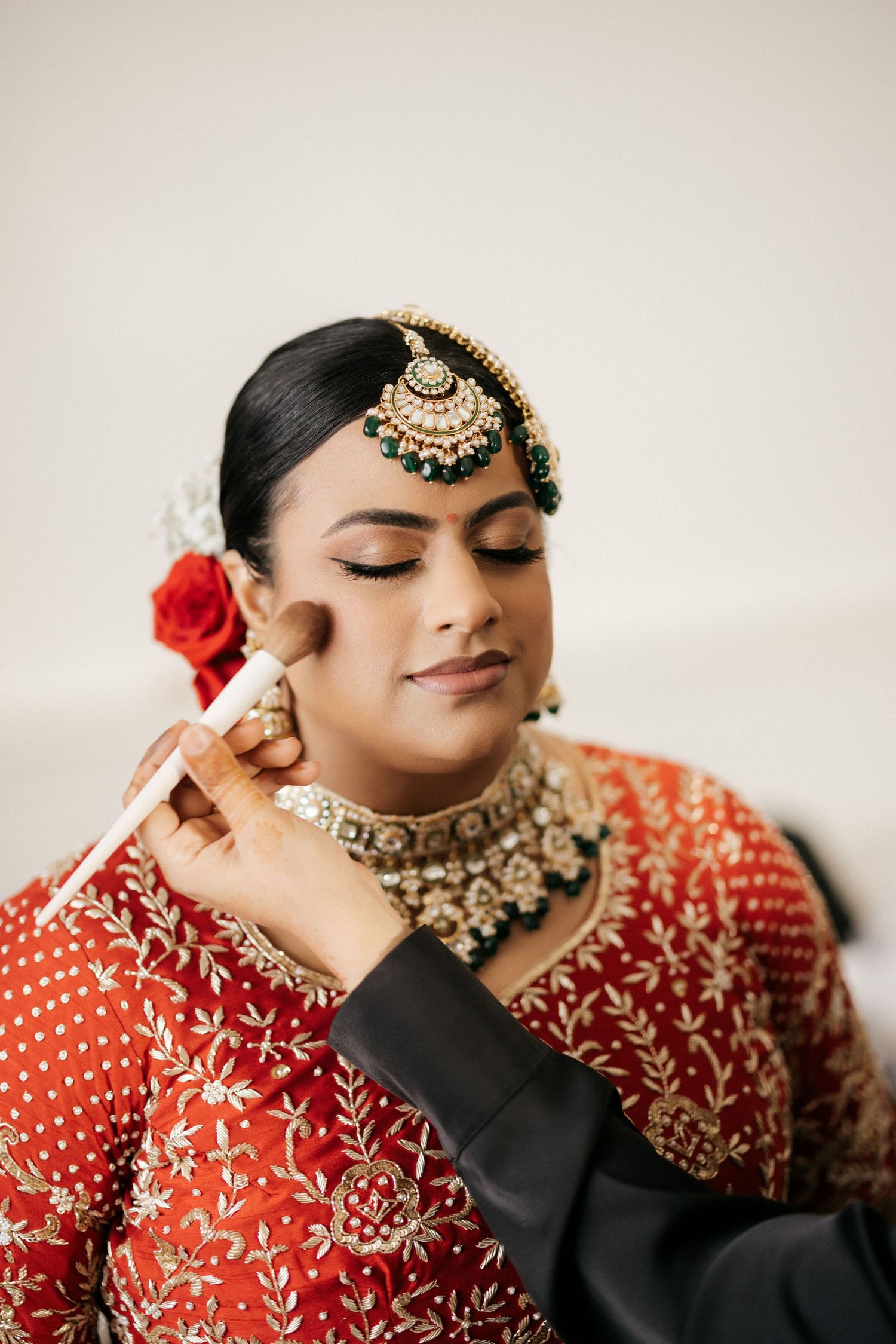 A close-up shot of traditional South Asian bridal jewelry and makeup being applied.