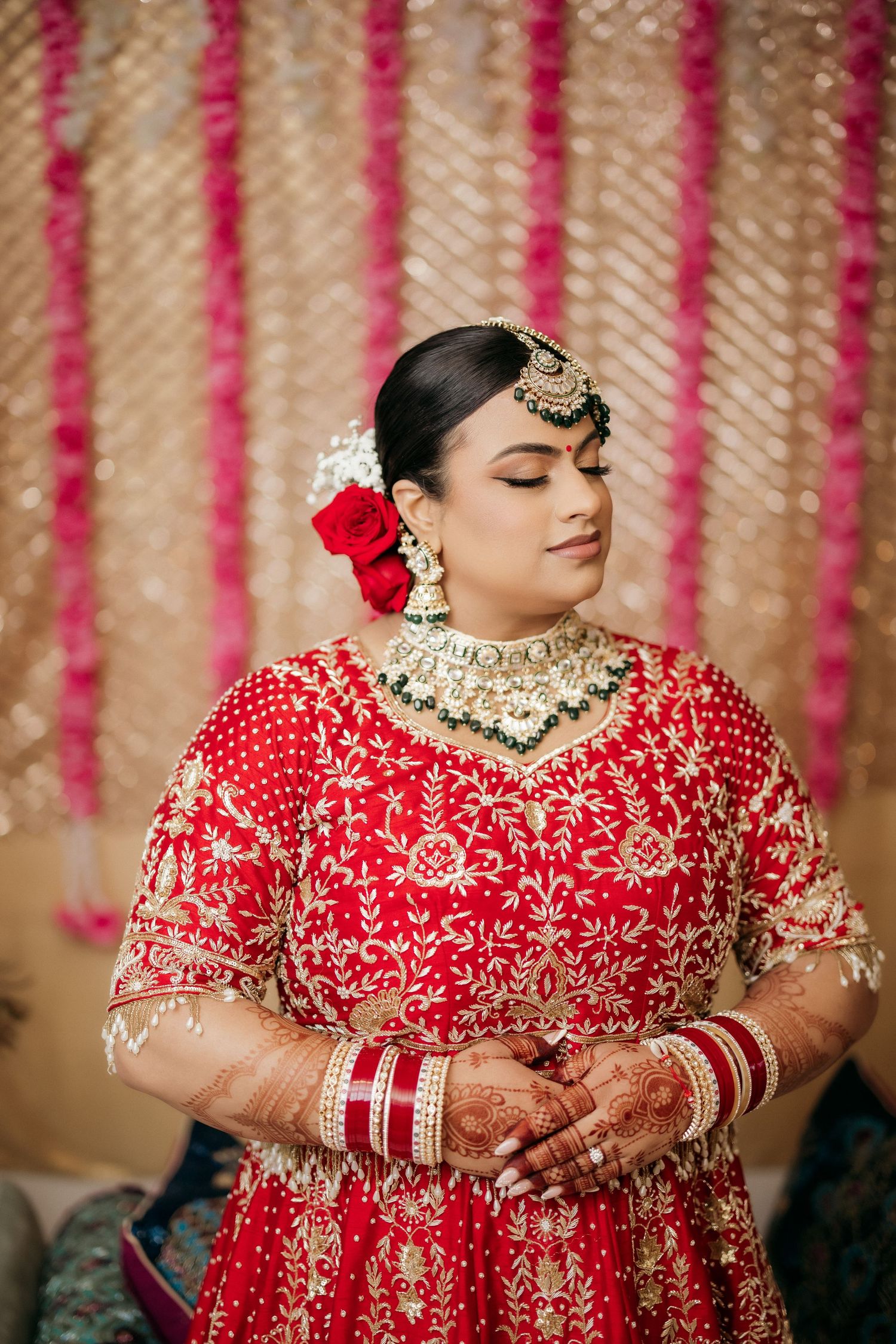 Elegant Indian bridal portrait featuring red lehenga, traditional jewelry, and floral hair accessories.
