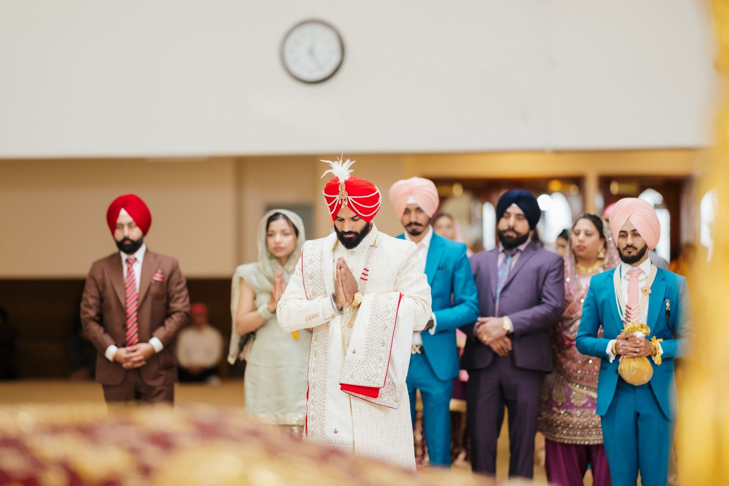 A group of guests in colorful traditional attire at a Sikh wedding ceremony.