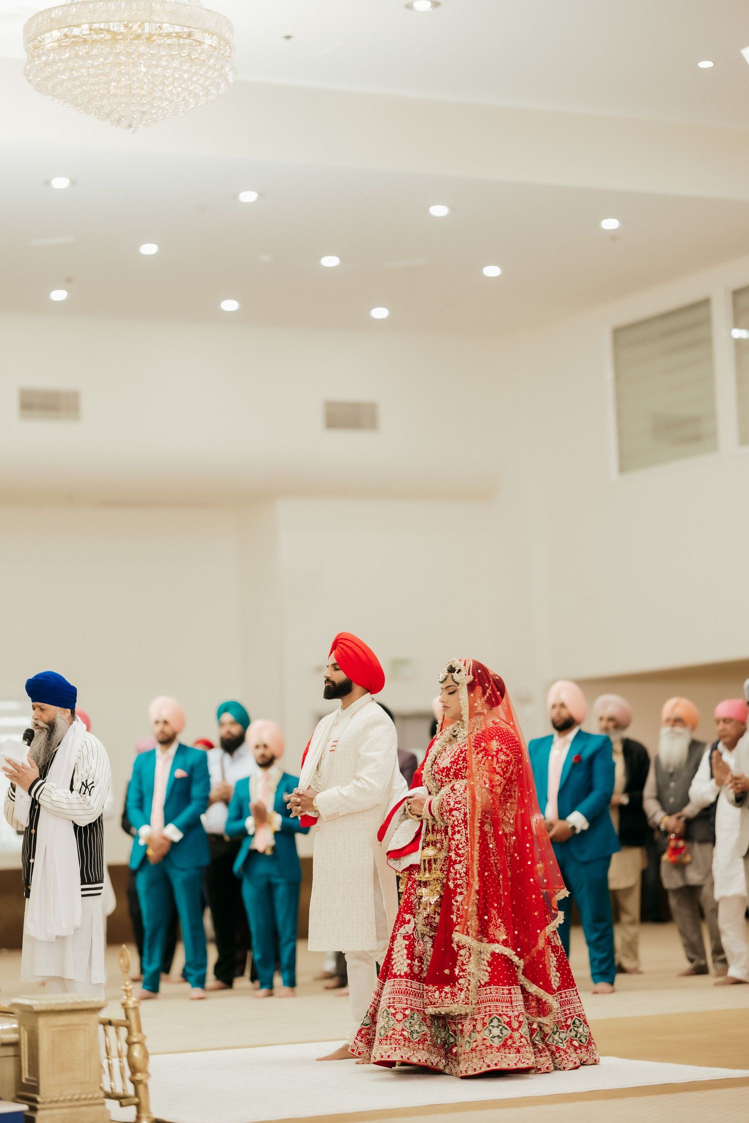 A Sikh wedding ceremony with guests in colorful attire watching the traditional proceedings.