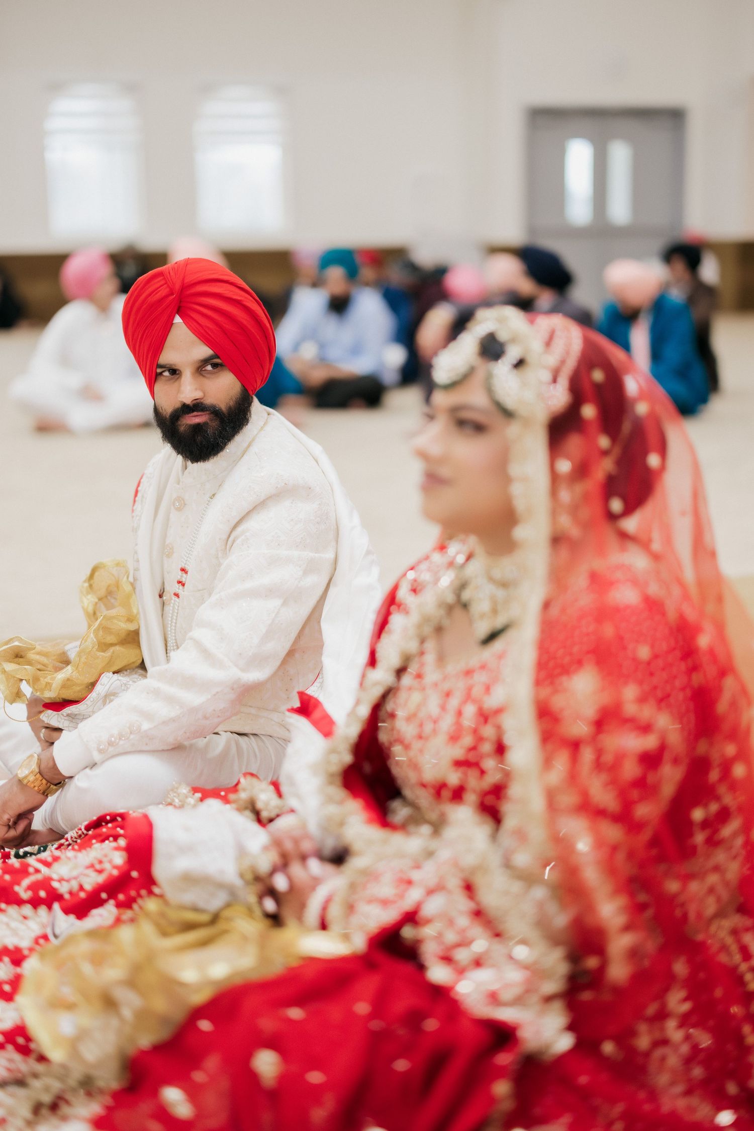 A Sikh wedding ceremony with the couple seated during traditional rituals in a temple.