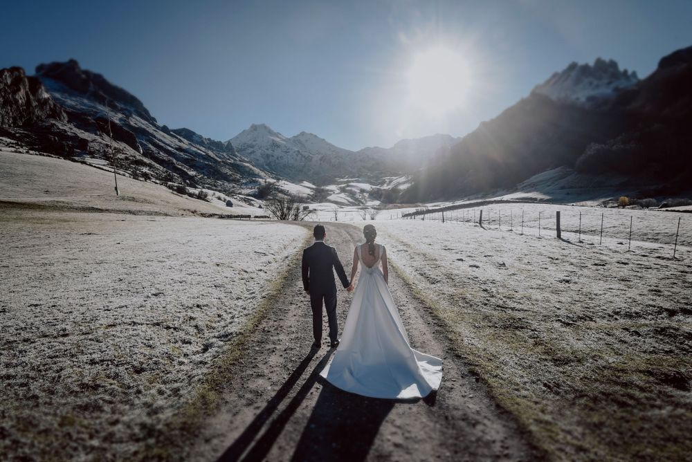 Postboda en Asturias en la montaña, pareja caminando juntos en Valle del Lago en Somiedo. Nevado con las montañas al fondo.