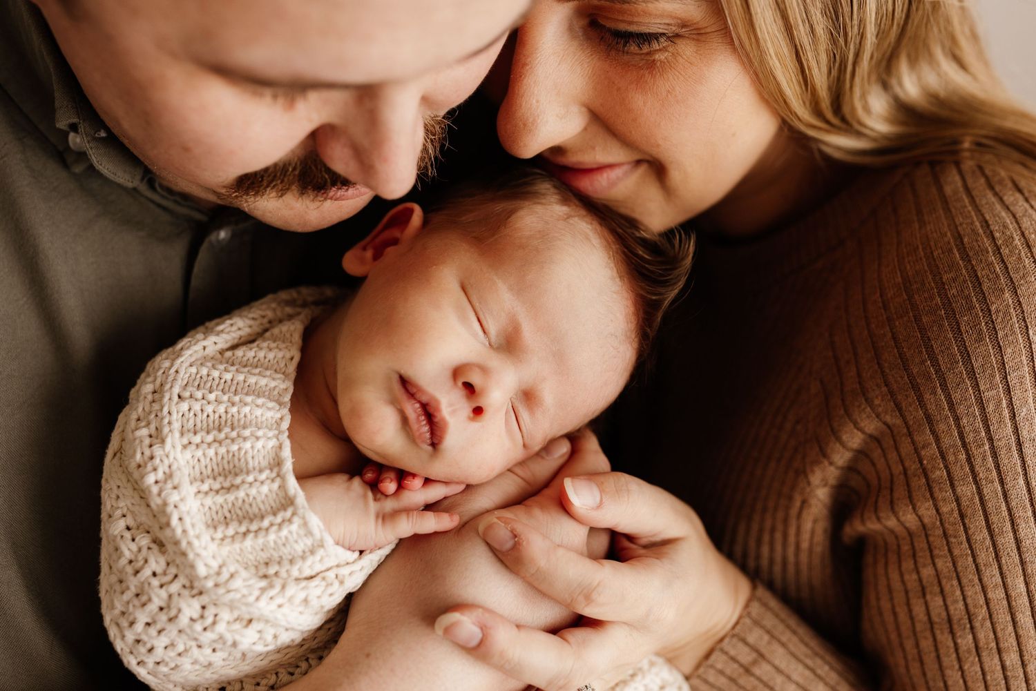 Intimate family portrait captured in warm brown tones showing tender connection.