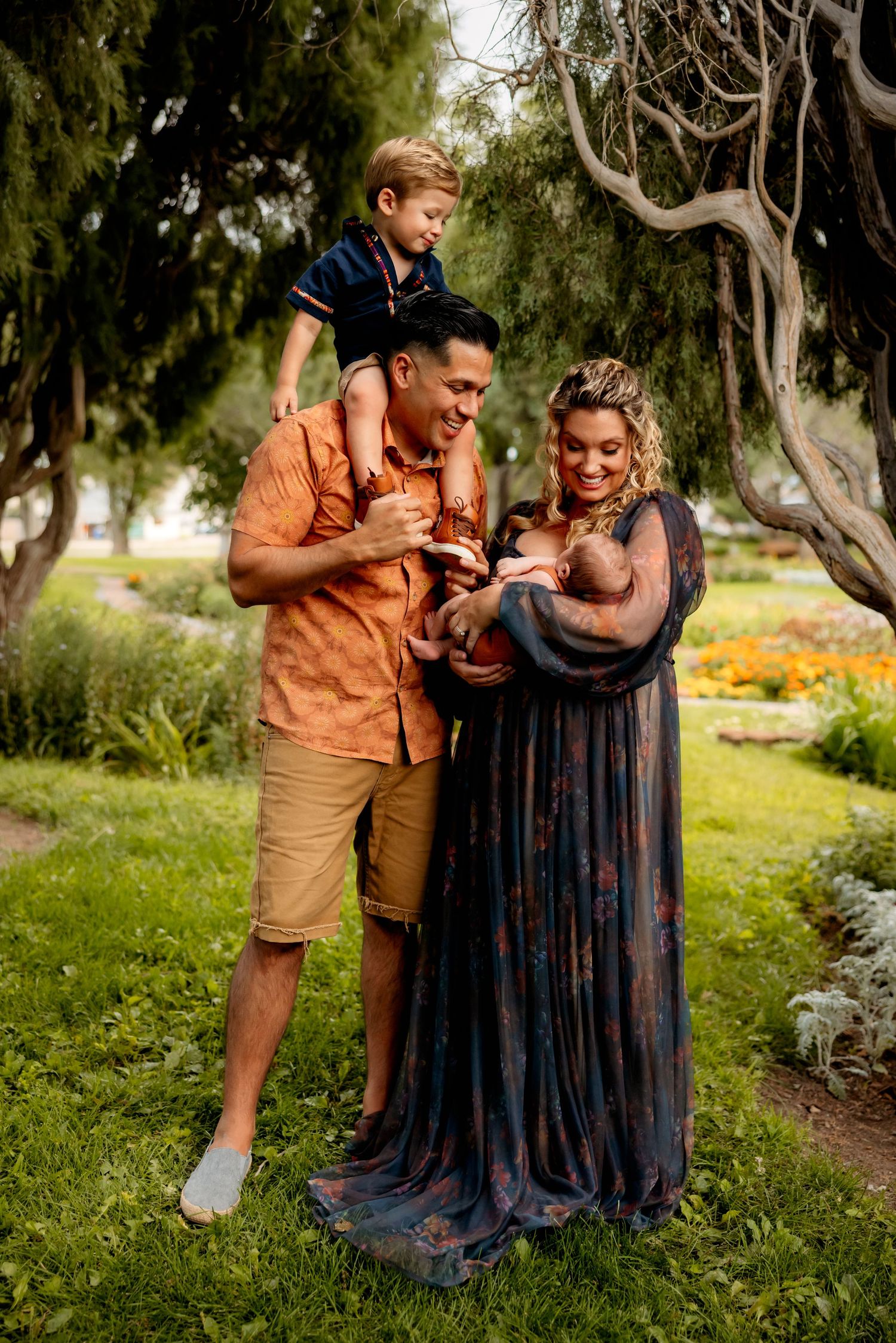 Family portrait in a garden setting with parents and children sharing a joyful outdoor moment.