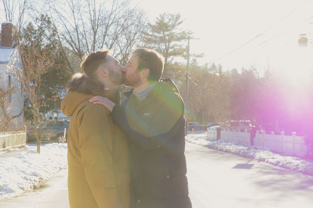 Romantic winter engagement photos with sunlight flares and snow-covered scenery.