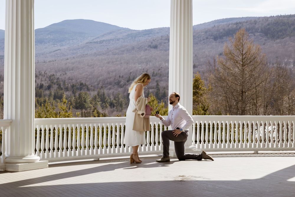 A romantic proposal scene on an elegant white columned porch with mountain views.