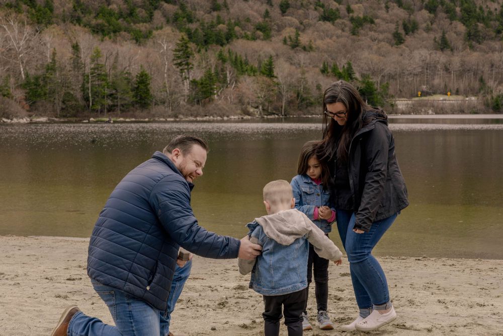 Family enjoying time together on beach near mountain lake.