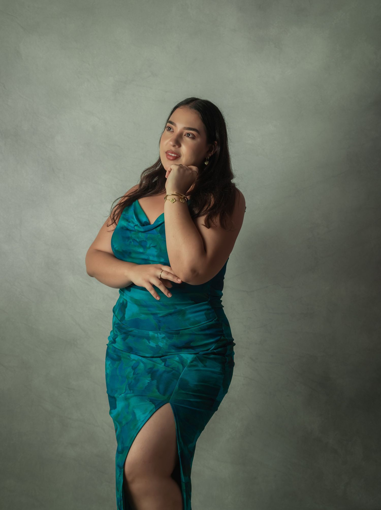 Elegant portrait featuring a person in a teal dress against a textured grey background.