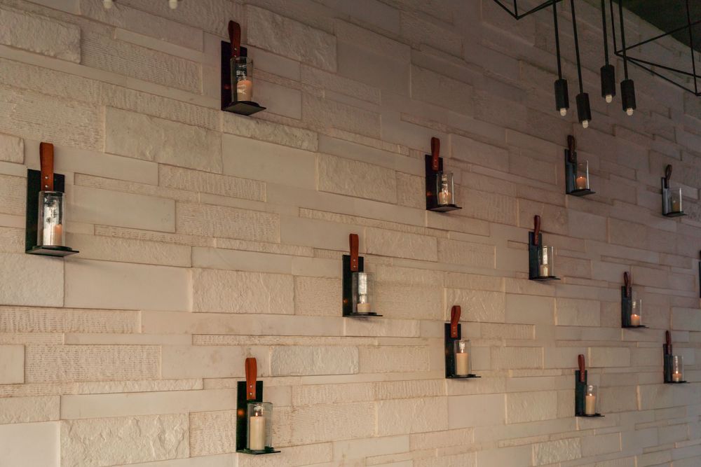 Wine bottles mounted on beige stone wall create artistic display.