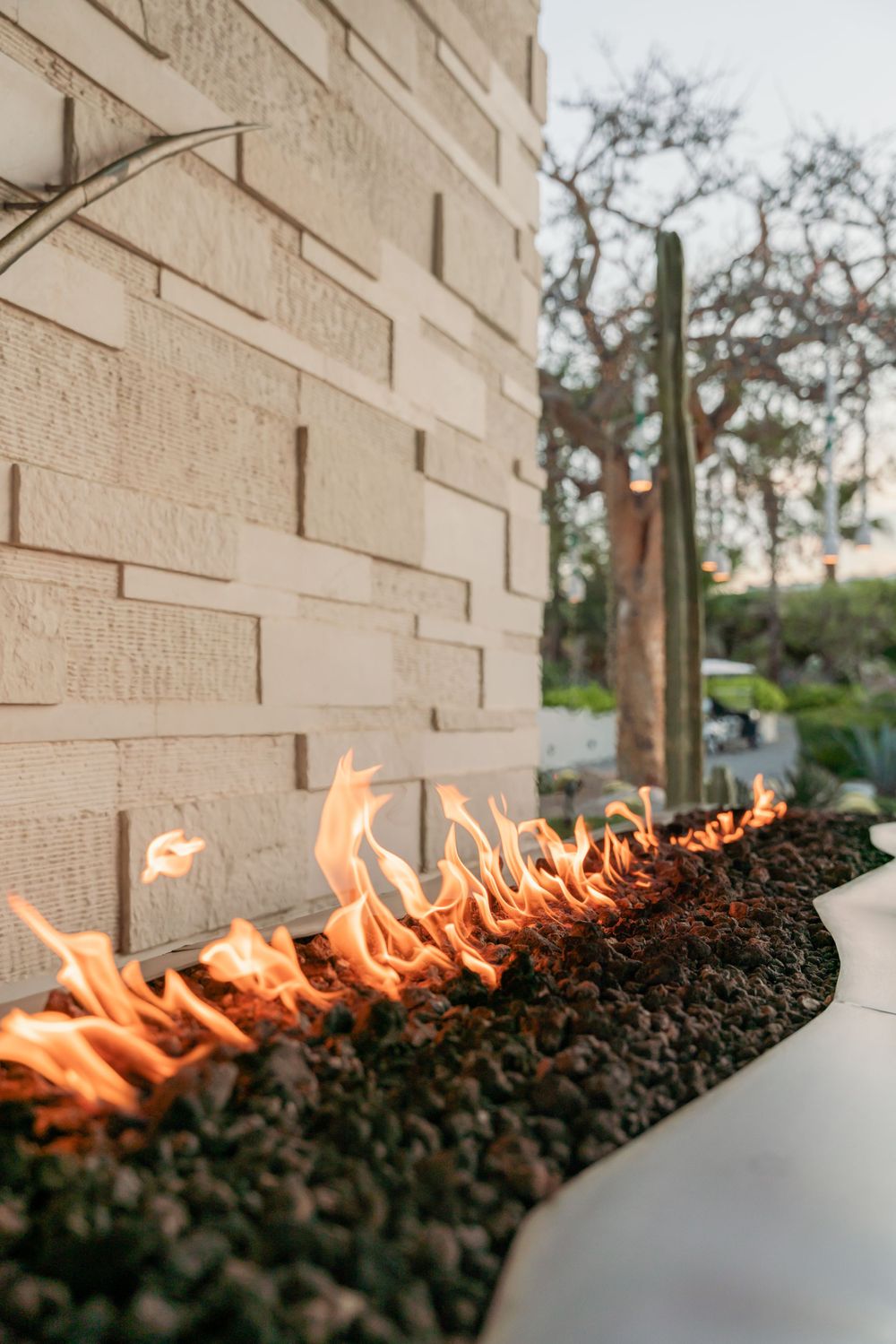 Modern fire feature with flames along textured stone wall creates ambiance.