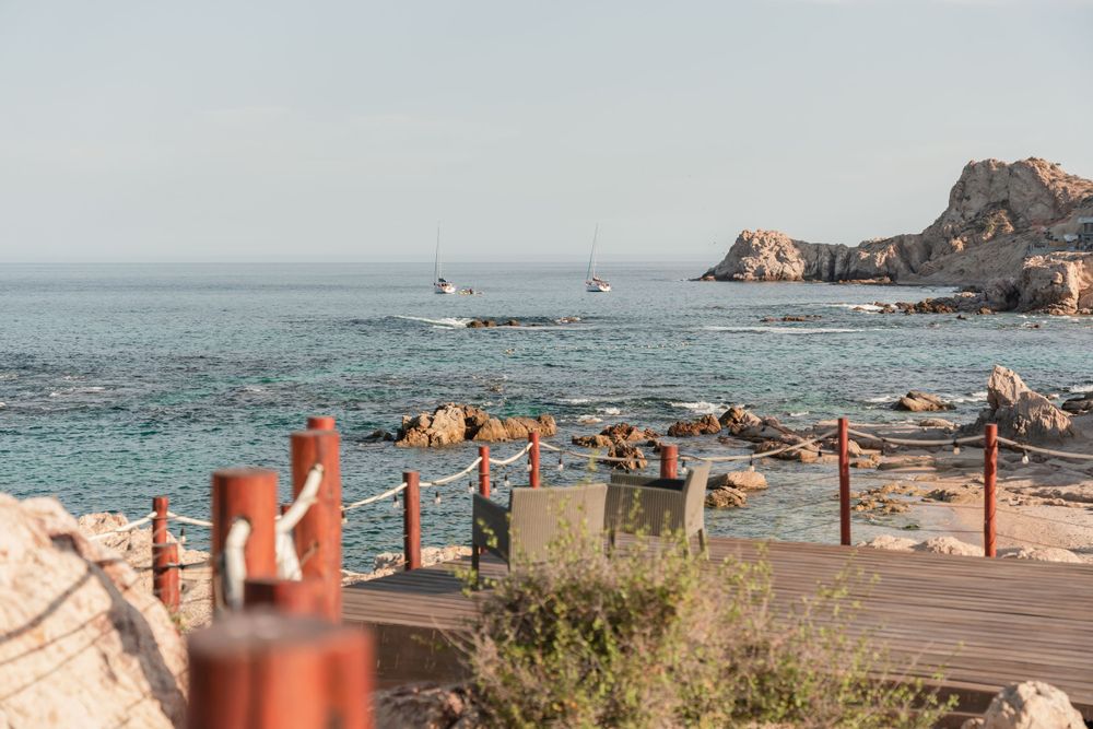 Scenic ocean view with wooden boardwalk and coastal rocks in foreground.