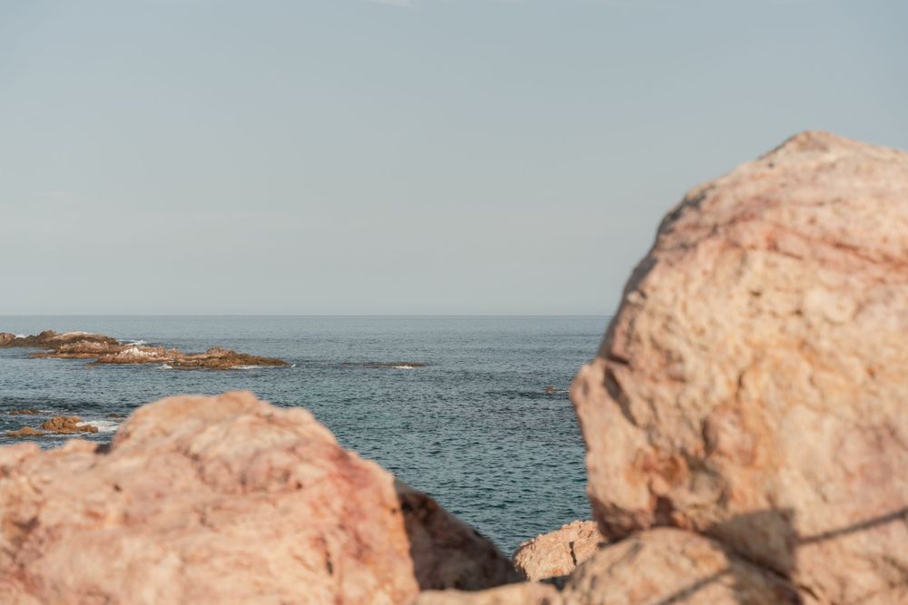 Rocky coastal landscape with blue ocean and clear sky.