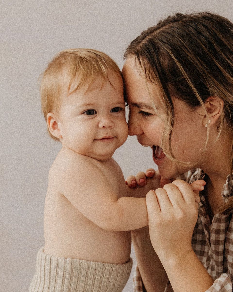 Tender moment captured between parent and child during casual indoor photo session.