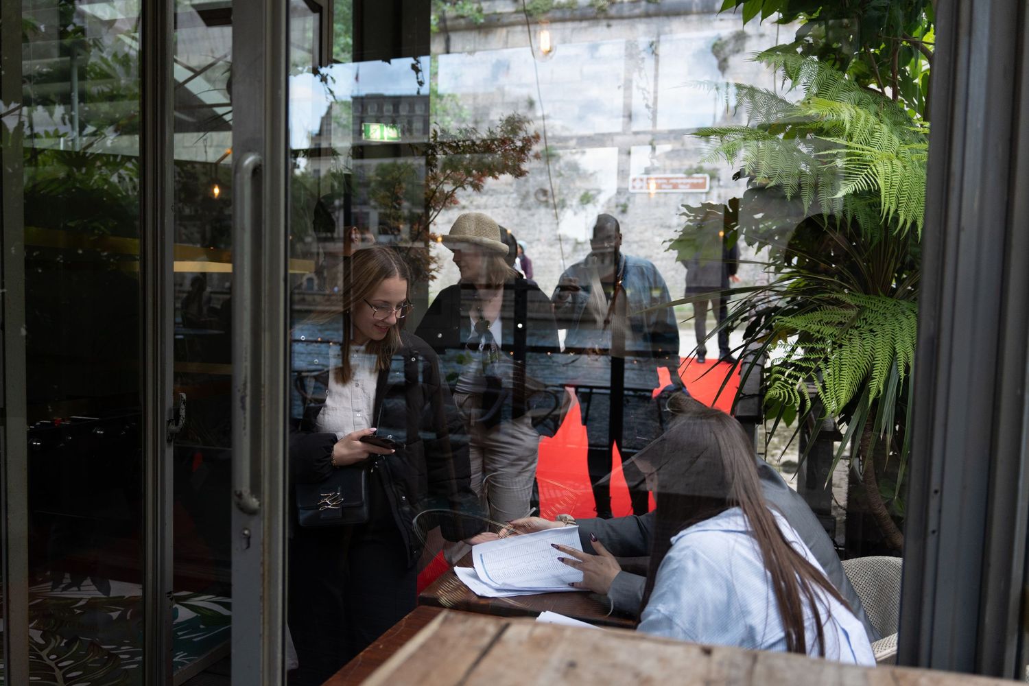 People meeting in a restaurant viewed through reflective window glass.