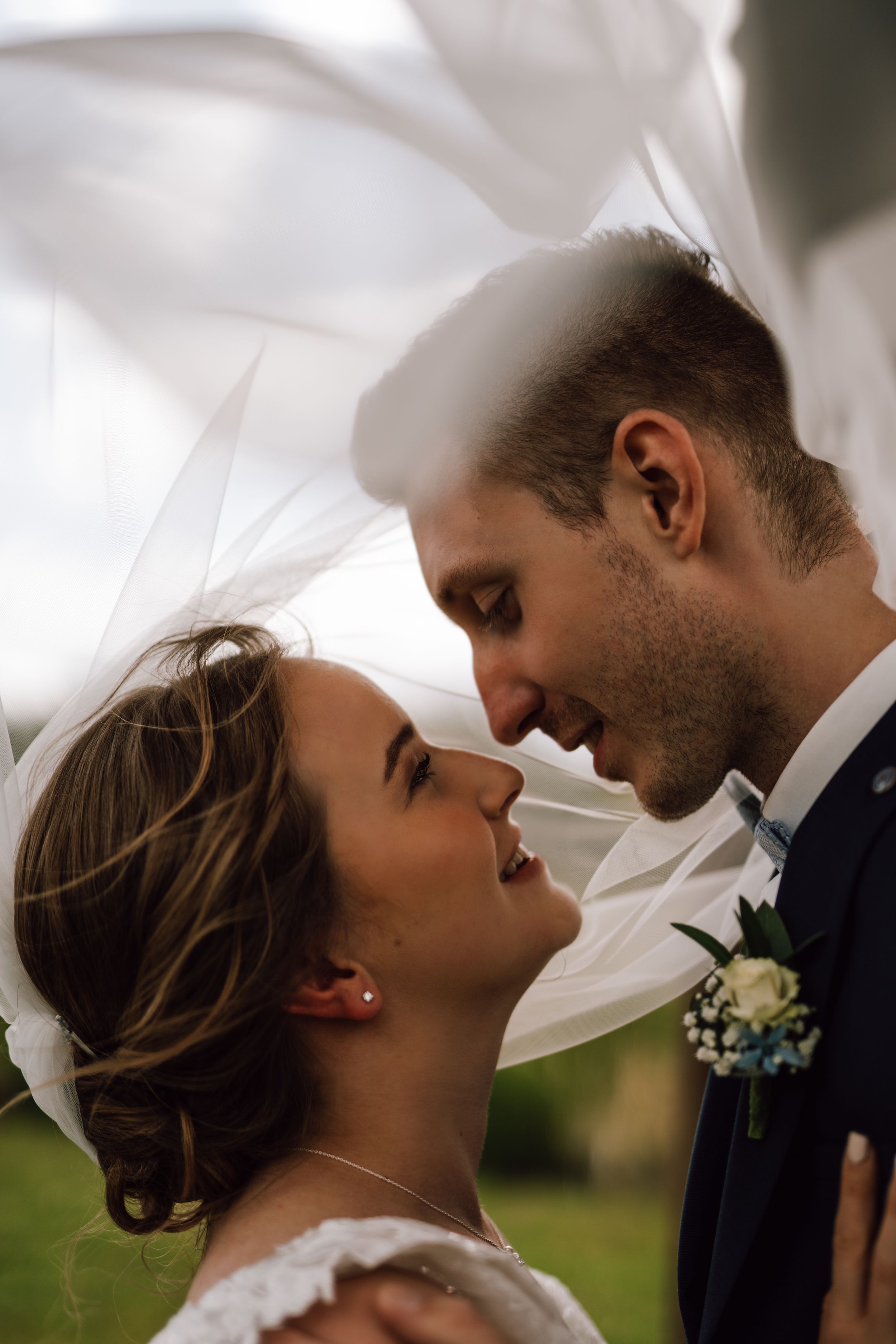 An intimate wedding portrait with a flowing veil creating a dreamy atmosphere.