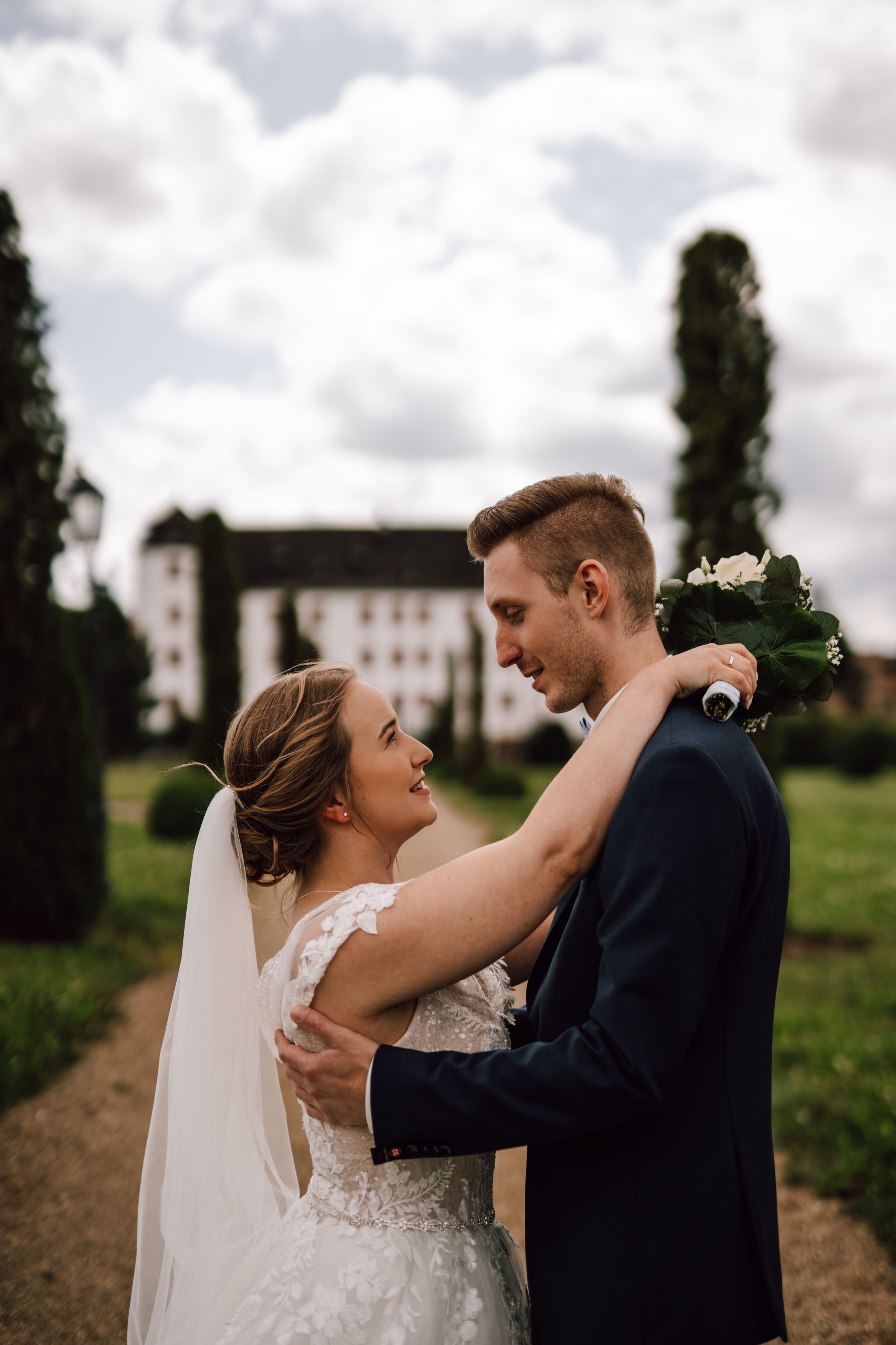 A couple shares a tender moment in an outdoor wedding setting with cloudy skies.