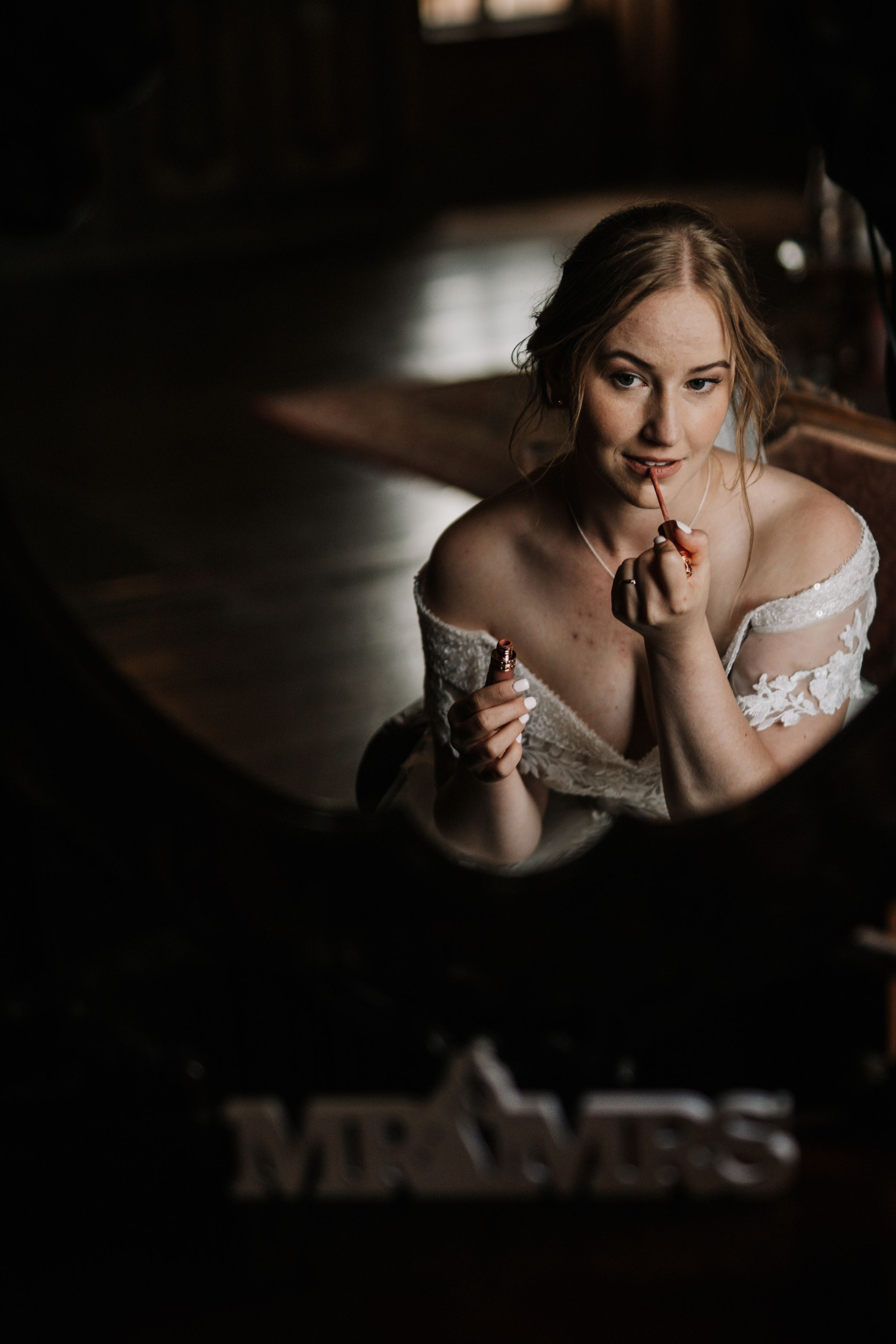 An artistic bridal portrait captured through a mirror reflection in moody lighting.