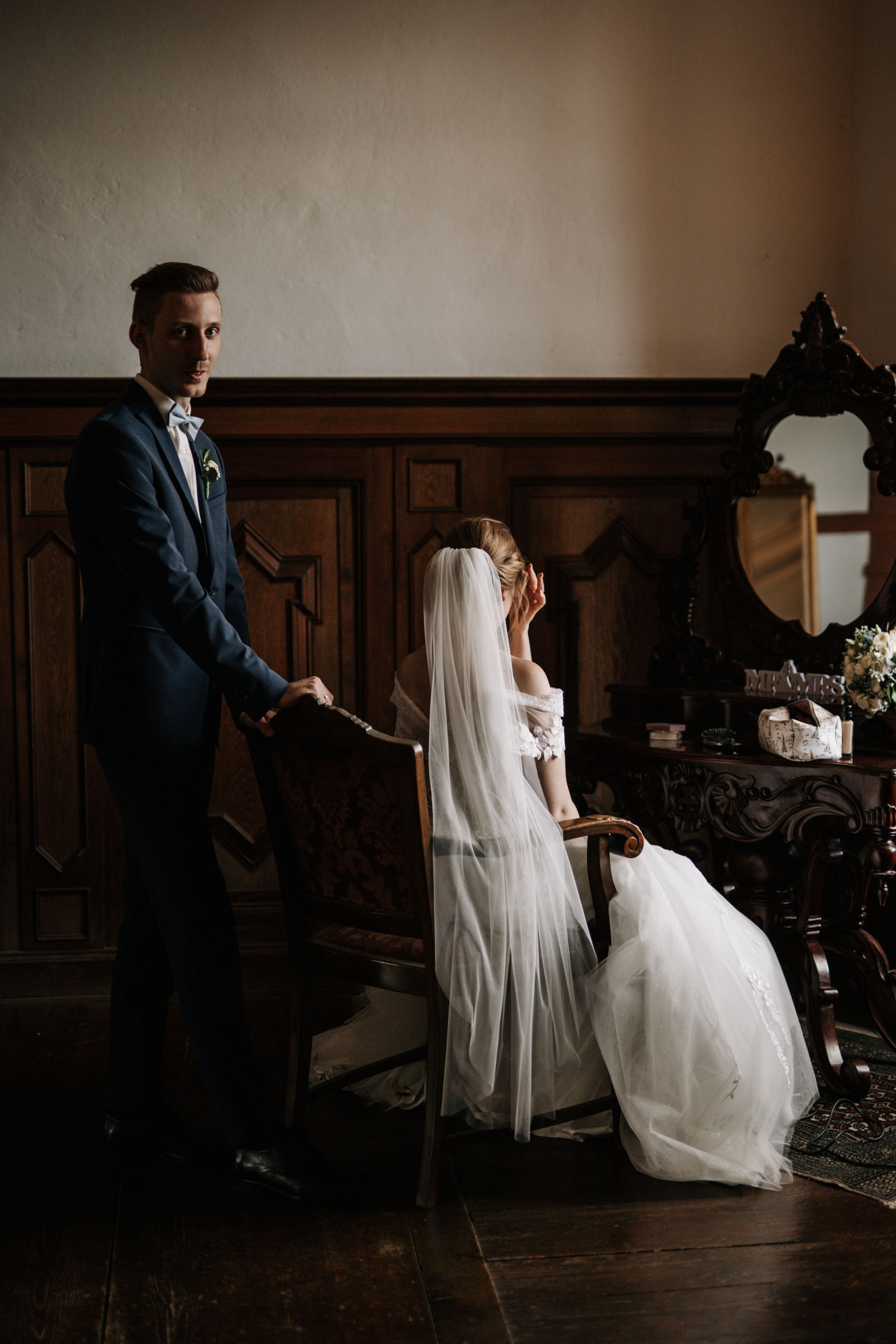 A stylish wedding couple posing in an elegant room with vintage wooden decor.