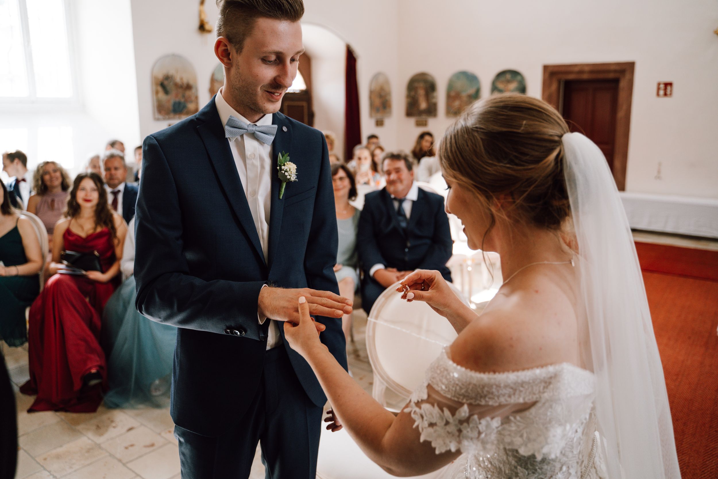 A tender moment during a wedding ring exchange ceremony in a church setting.