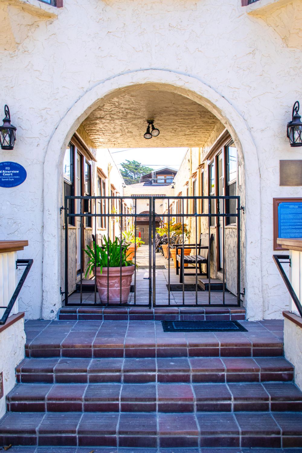 White stucco archway entrance with wrought iron gate and terracotta steps.