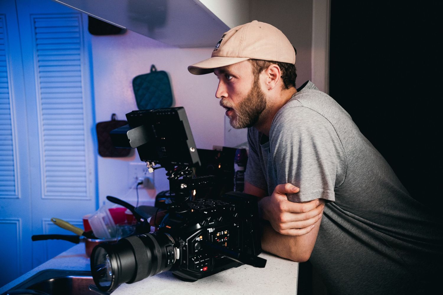 Camera operator working with professional video equipment in dim lighting.