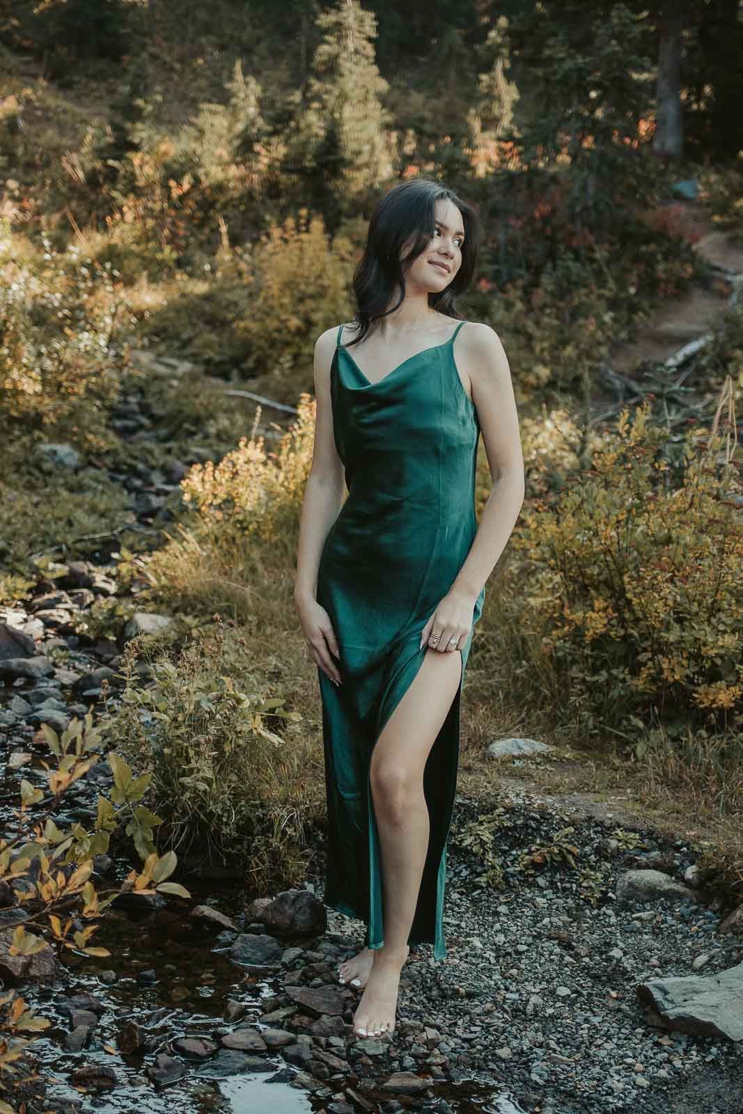 brown haired girl in long green silk dress in the mountains