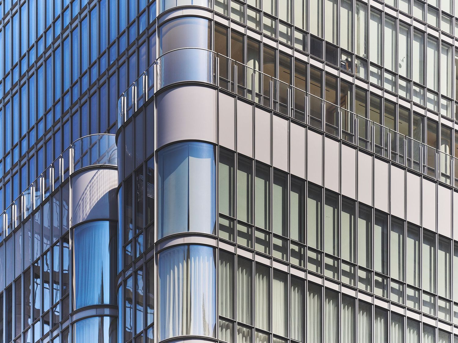 Modern office building facade featuring repeating pattern of glass windows and metallic vertical supports.