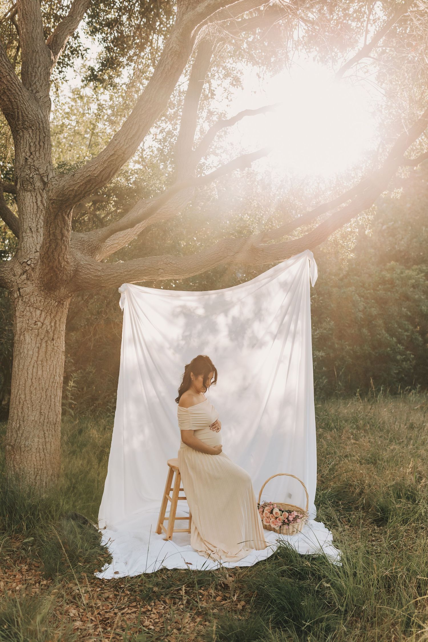 An expectant couple walks together in a romantic forest setting during a maternity photoshoot.