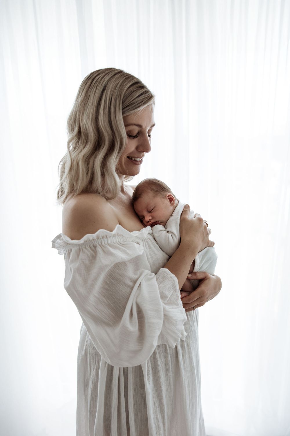 backlit Mother and newborn baby wearing white, Candid