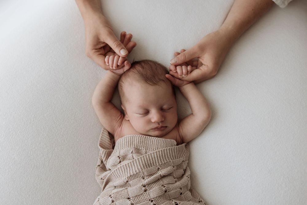 Newborn baby holding mothers hands