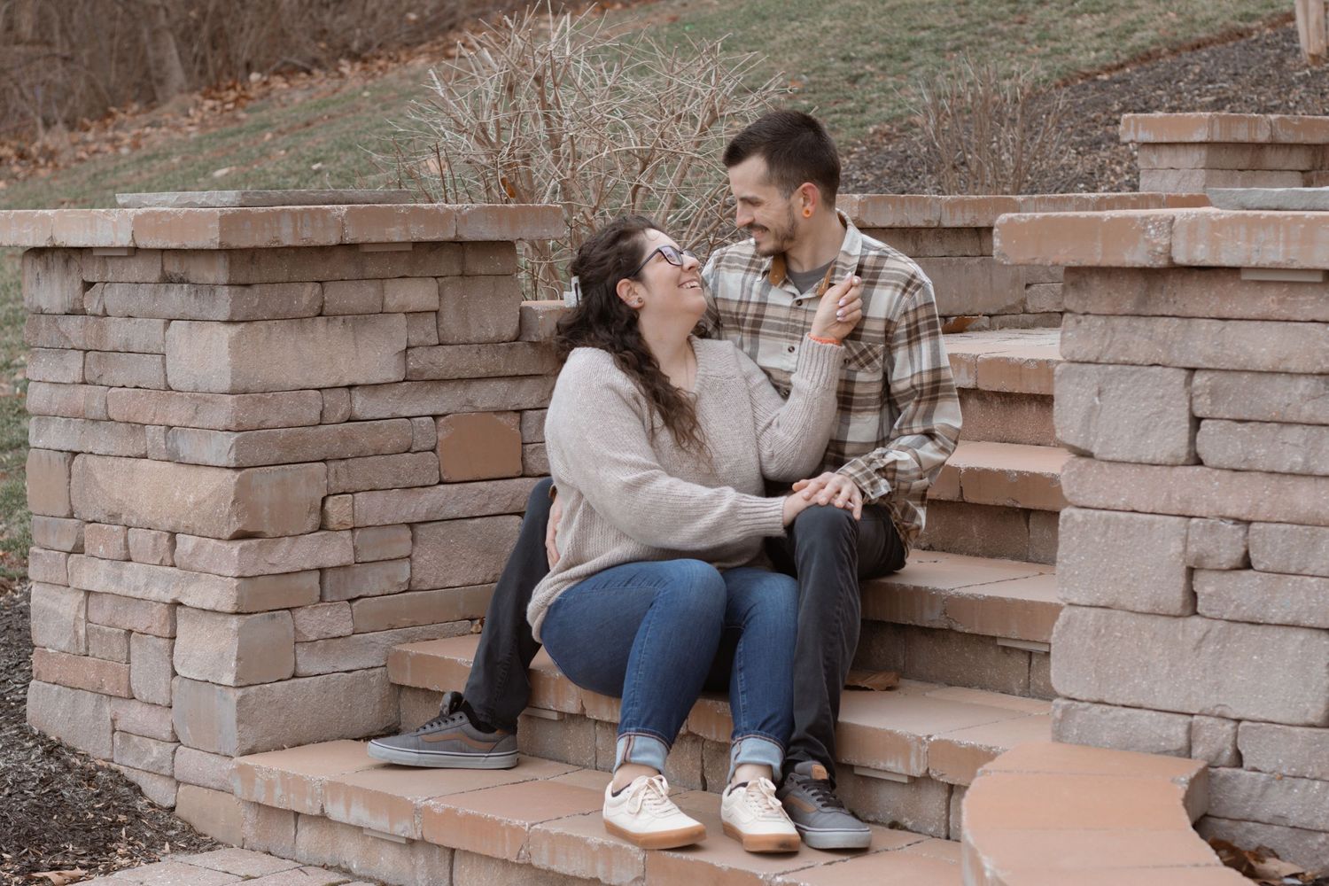 Couple sitting on stone steps during rustic outdoor photoshoot.