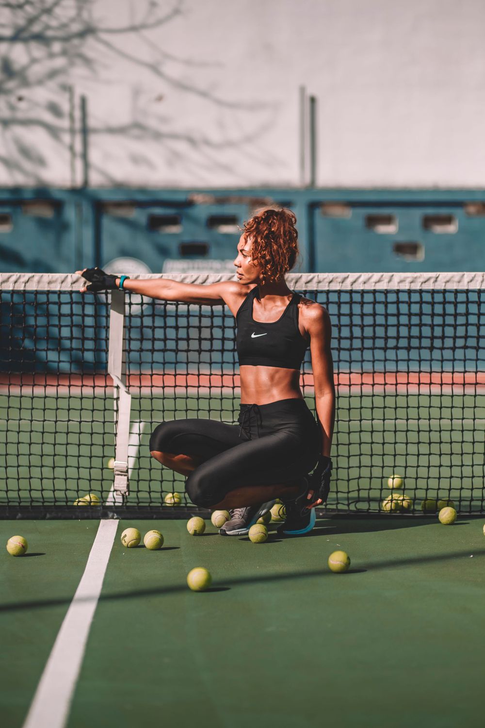 Athletic scene on tennis court with scattered tennis balls and sports equipment.
