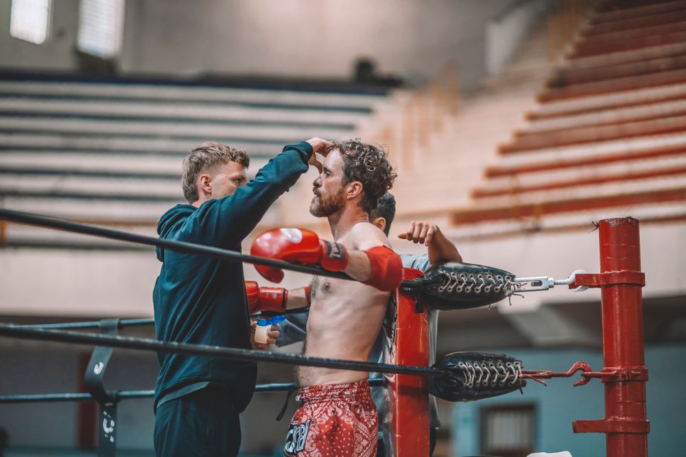 Two boxers training in a boxing ring with stadium seating in background.