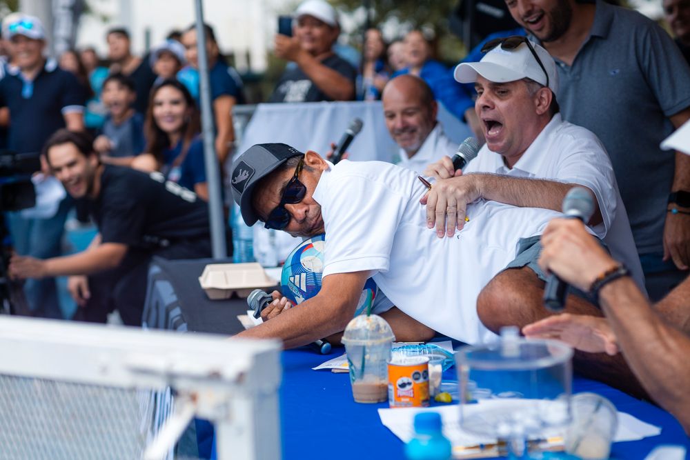 Baseball players signing autographs through a fence at a stadium.