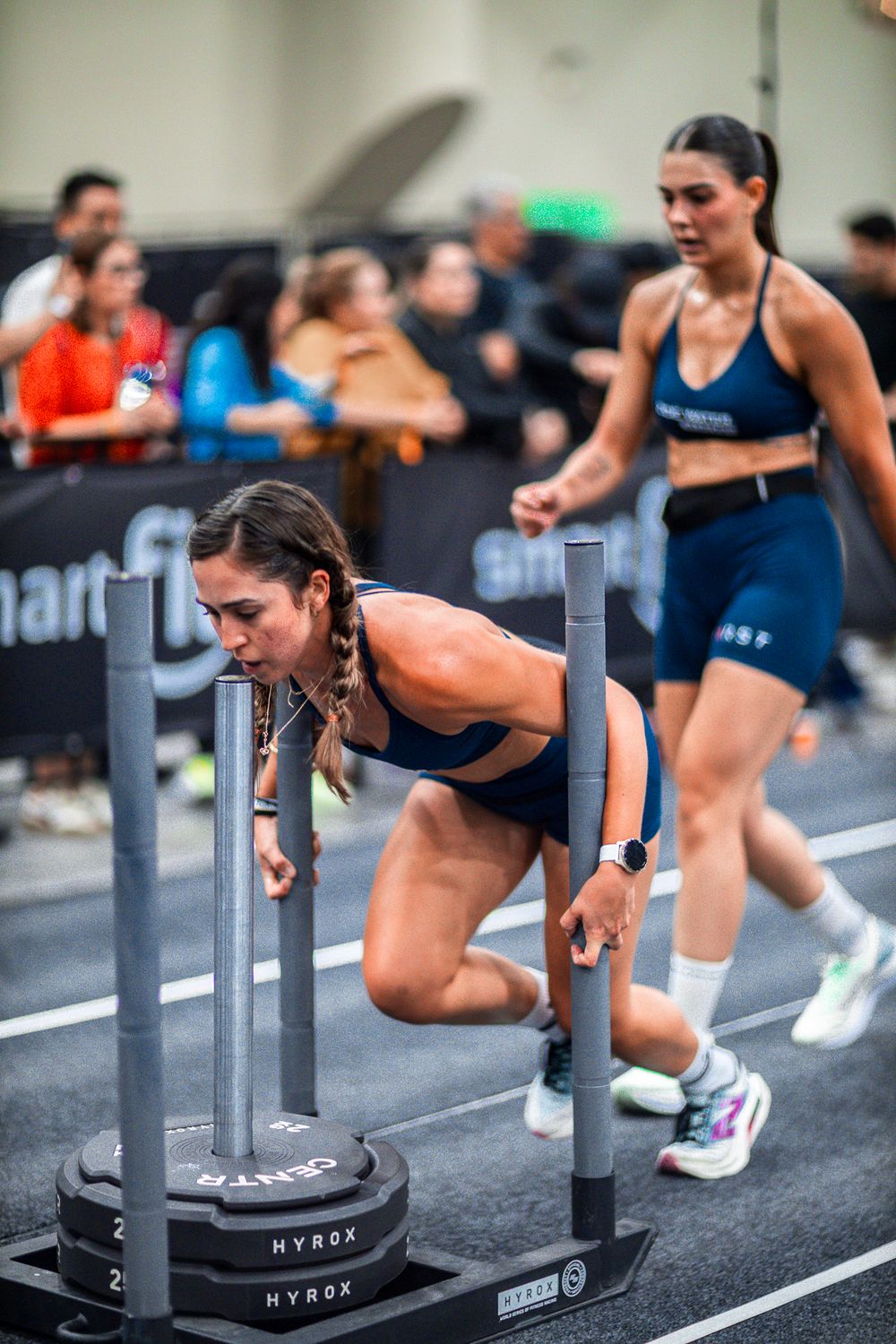 Athletes perform burpee box jumps during an intense CrossFit workout sequence on gym floor.