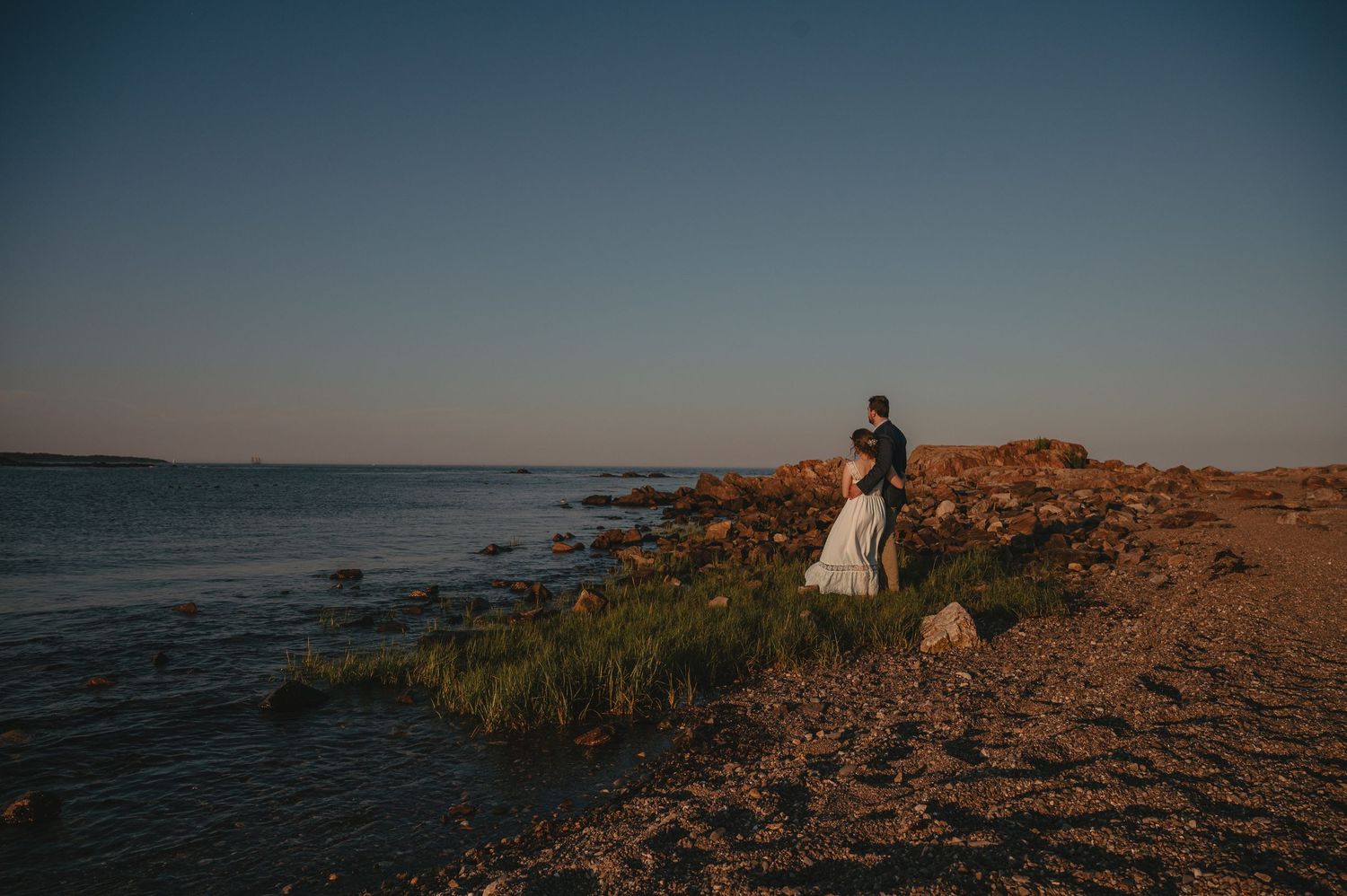 Bride and groom share a kiss between grand stone columns in a stunning wedding portrait.