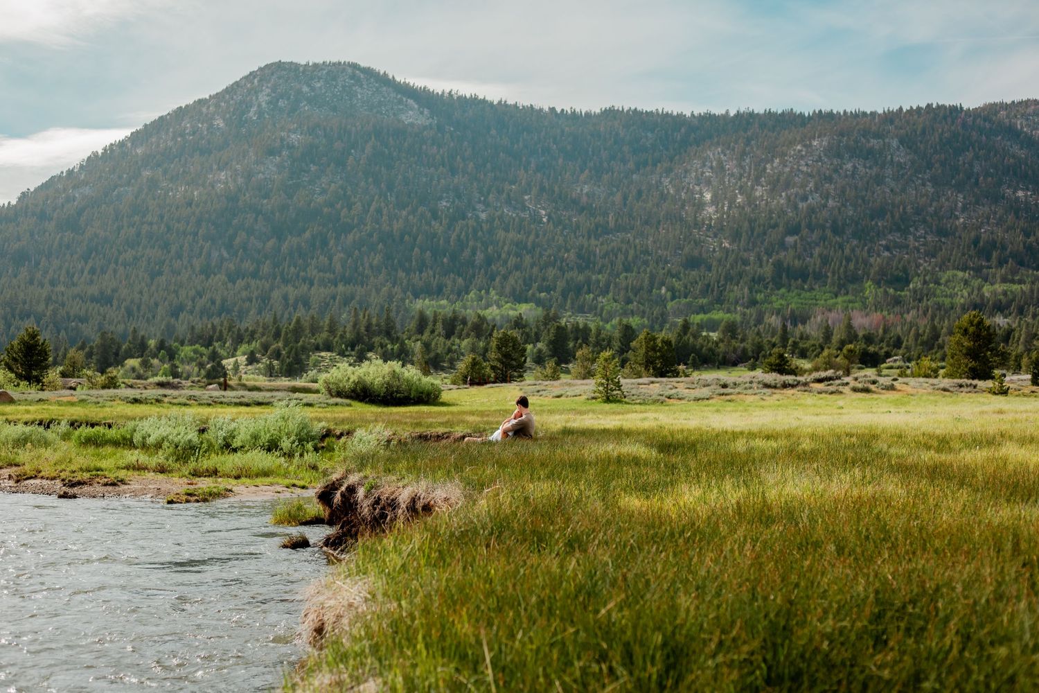 Scenic mountain landscape with grassy meadow and lake in foreground.