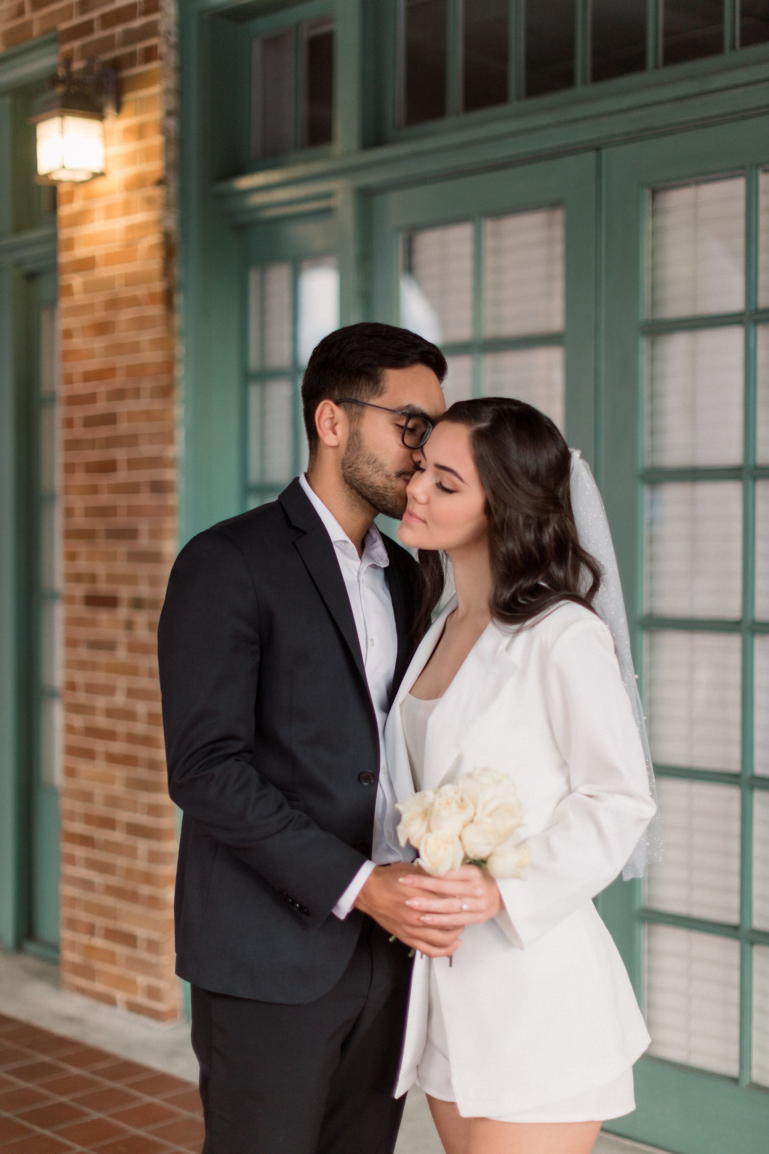 A couple shares intimate moment while holding white flowers.