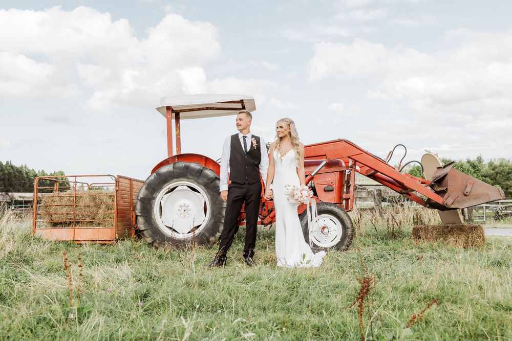 Farm and Backyard wedding at Tauranga Wedding Photographer. Bride and groom is standing next to the tractor