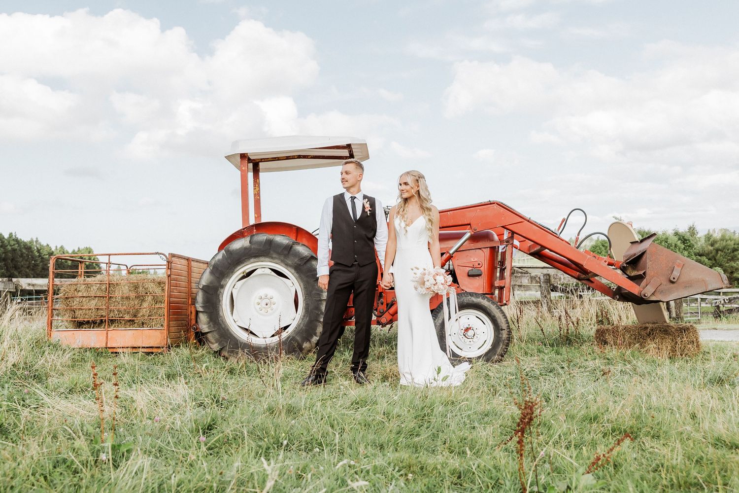 Farm and Backyard wedding at Tauranga Wedding Photographer. Bride and groom is standing next to the tractor