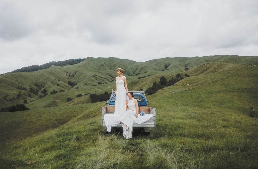 LGBTQ+ Same-sex wedding: brides riding in the back of a truck while exploring their farm. Auckland photographer.