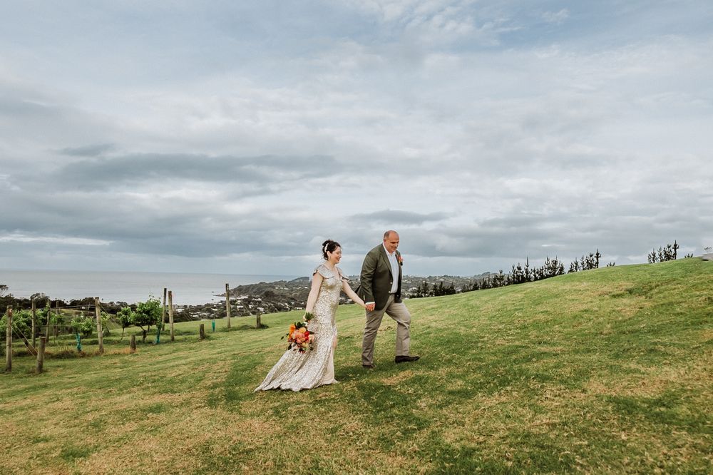 Bride and Groom Walking at the vineyard at Mudbrick Waiheke wedding venue. Wedding photographer