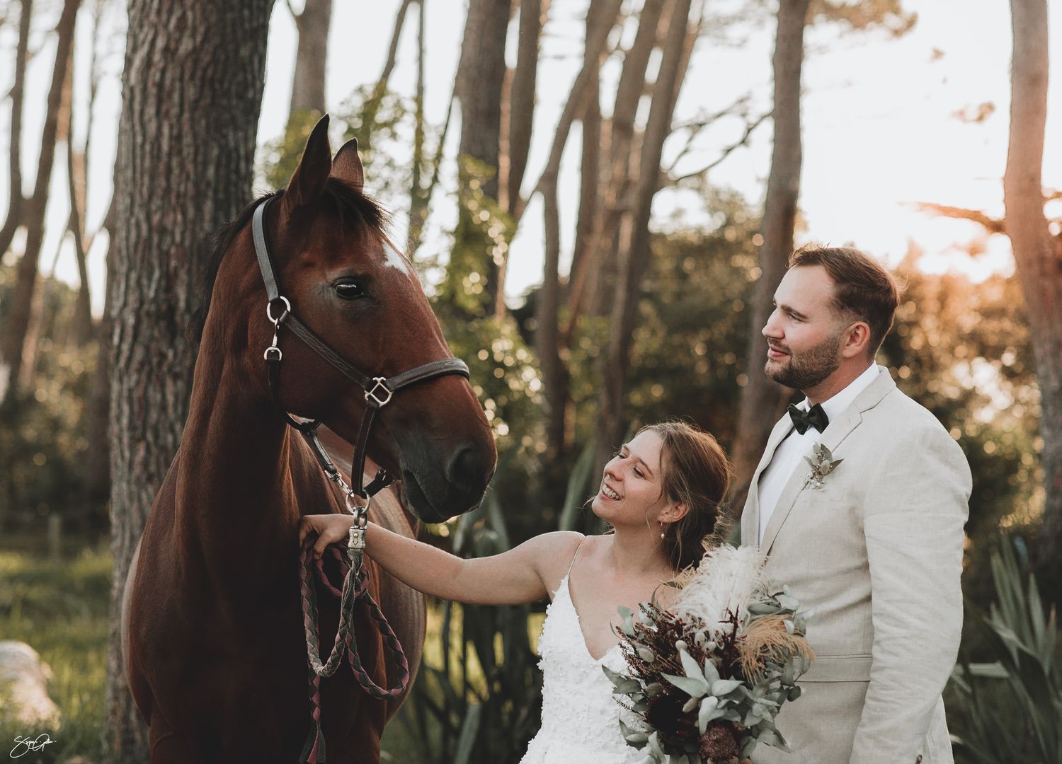 bride and groom with the horse smiling at Muriwai beach. AUckland Wedding Photographer