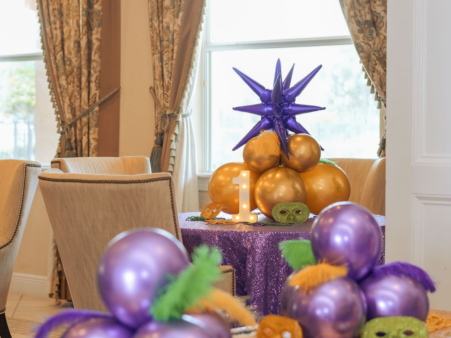 Purple and gold balloons surround a sparkling purple cake stand with a star topper.