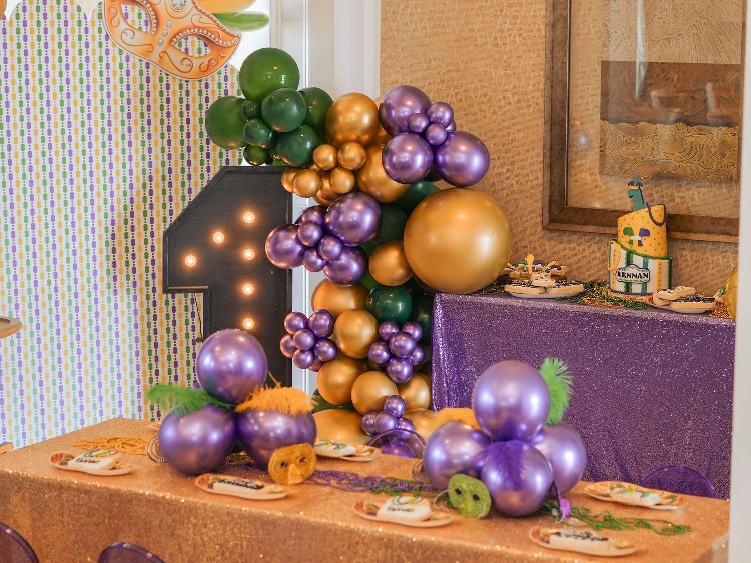 Elegant party setup with purple and gold balloon arch, decorative lighting, and party favors.