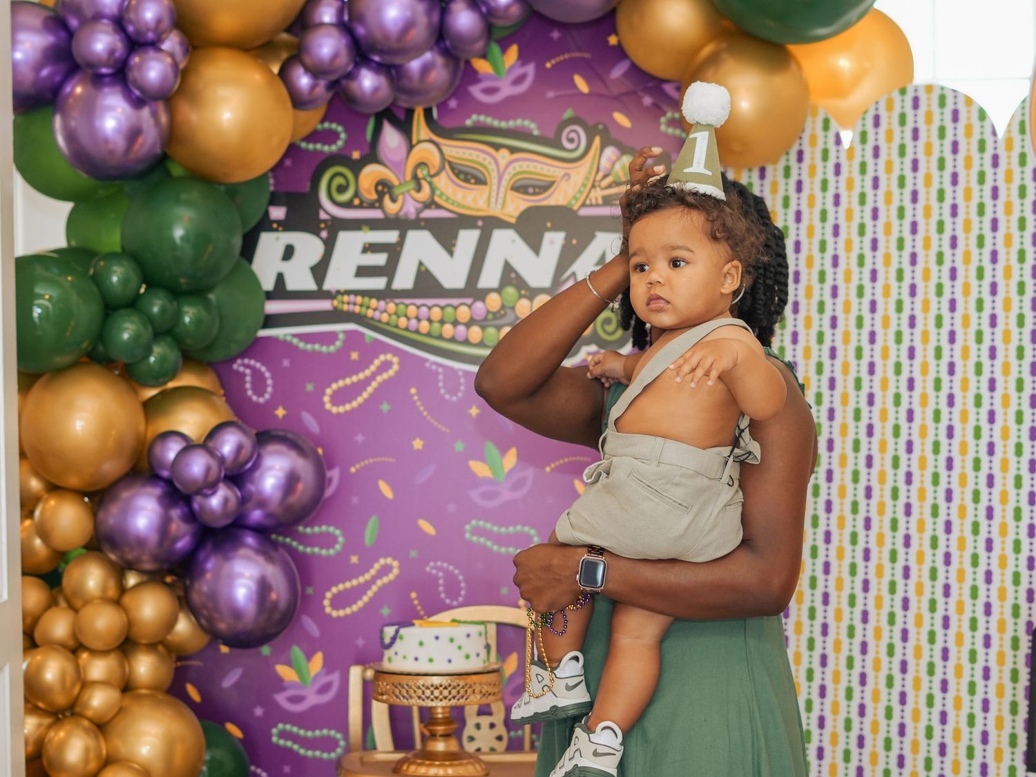 Festive balloon arch display with purple and gold colors against a custom backdrop.